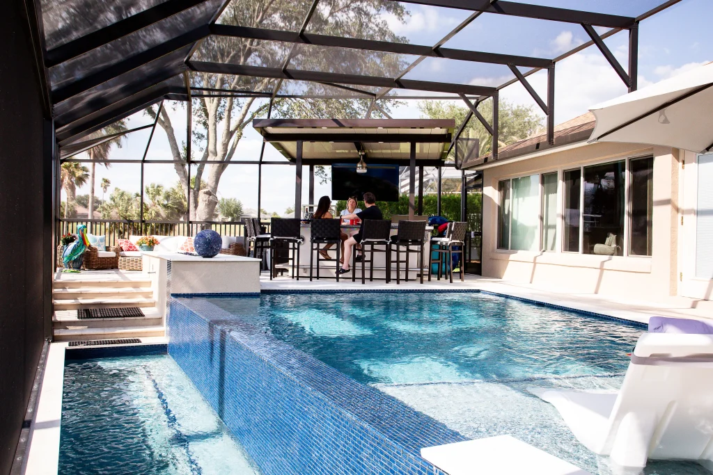 Luxury backyard pool in winter park with a sunshelf and overflow spool with no pool design mistakes.