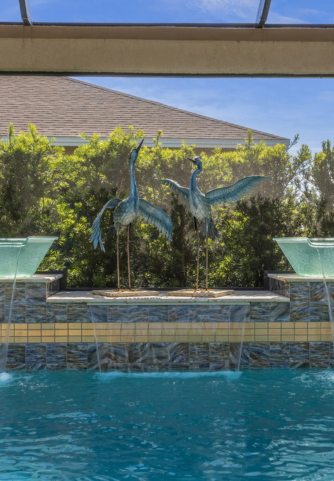 Heron statues with water bowls and waterfall features spilling into pool