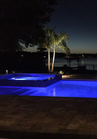 Deep blue lighting illuminating modern pool and hot tub in Florida