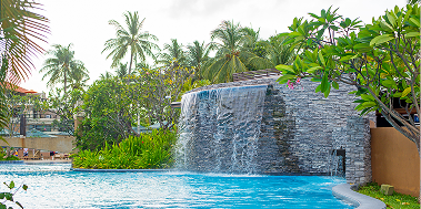 Tall pool waterfall with lots of foliage around
