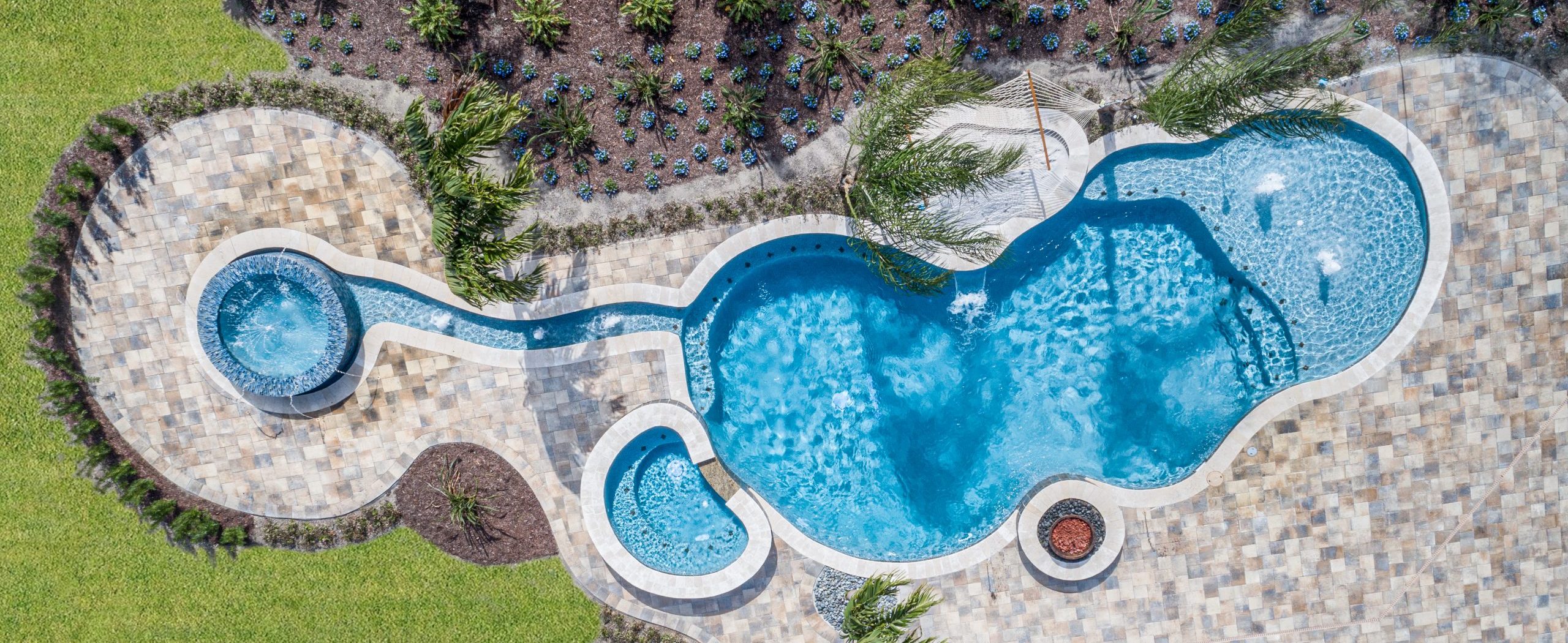 Freeform pool with tile decking, hot tub, and multiple water features in Florida