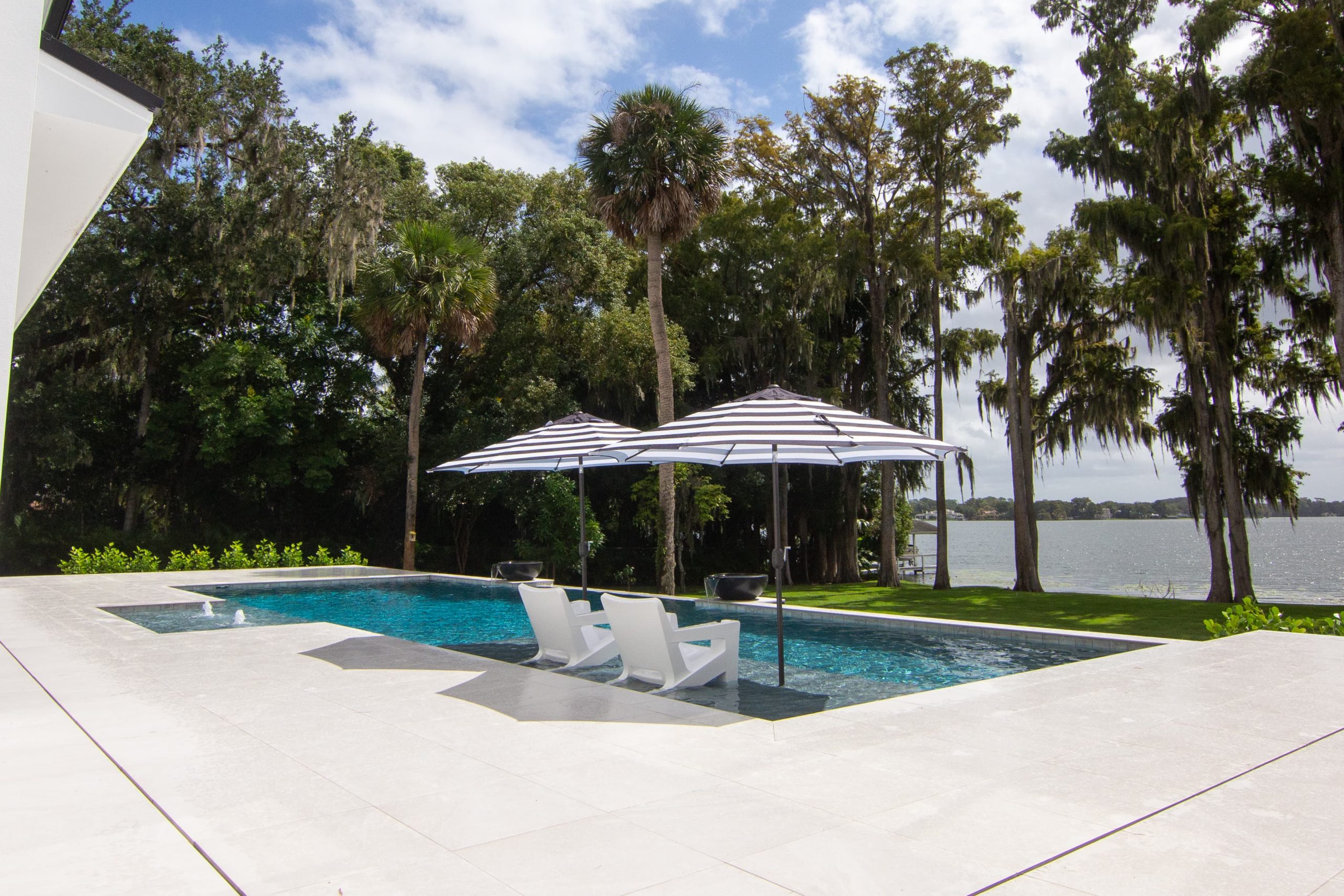 Custom winter park pool with sun shelf and umbrellas over chairs on the water