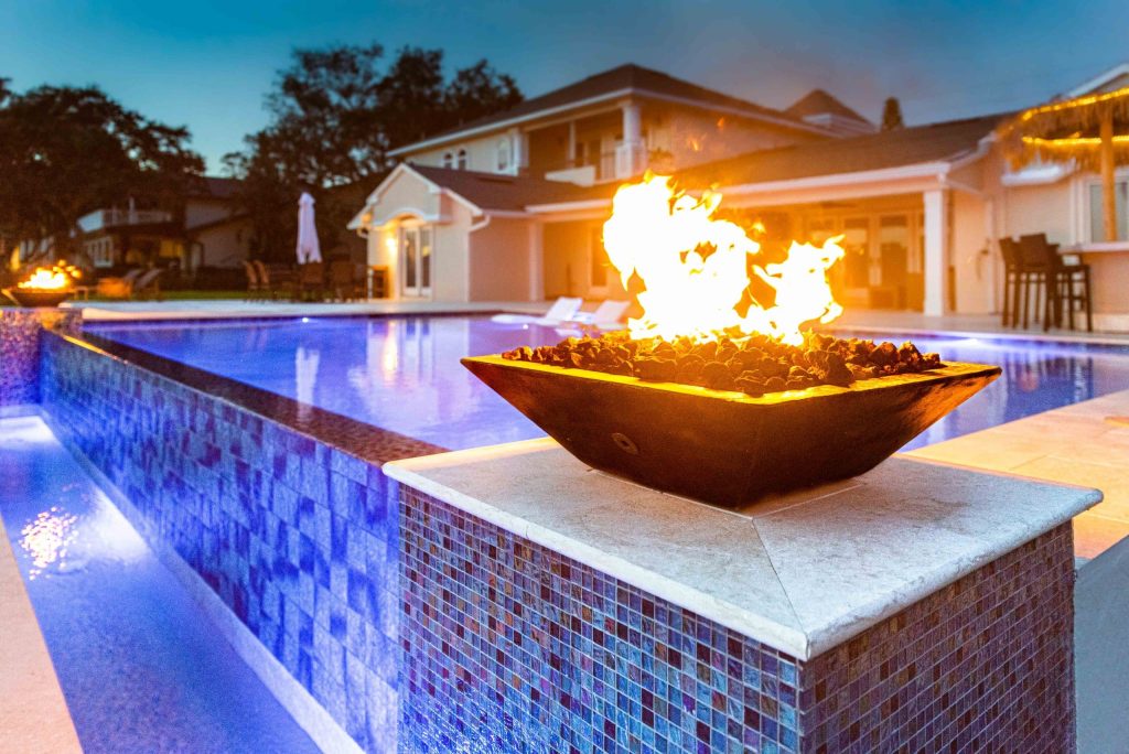 Custom pool features in orlando like a fire bowl on an infinity pool
